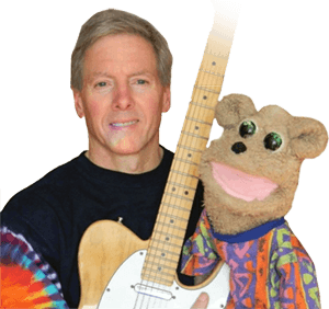 Kim Webster sits with his electric guitar and a puppet called Ted Bear.